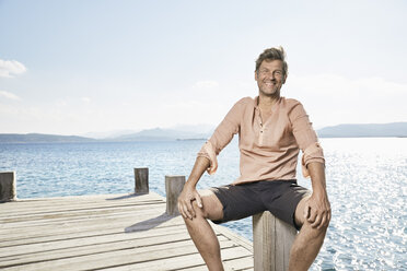 Portrait of smiling man sitting on jetty - PDF01205