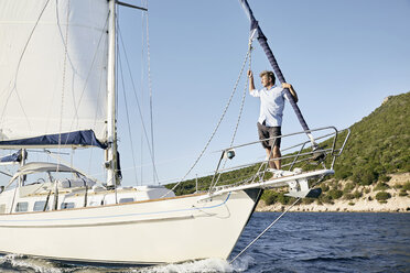 Man standing on bow of his sailing boat looking at distance - PDF01211