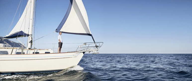Mature man standing on his sailing boat looking at distance - PDF01217