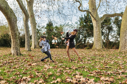 Mutter spielt mit ihrer Tochter im herbstlichen Park, lizenzfreies Stockfoto