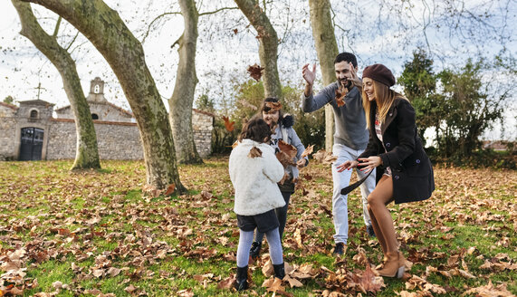 Familie spielt mit Herbstblättern in einem Park - MGOF03180