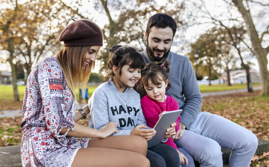 Familie sitzt auf einer Bank im herbstlichen Park und schaut auf eine Tafel - MGOF03184