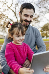 Father and little daughter taking selfie with tablet in autumnal park - MGOF03186