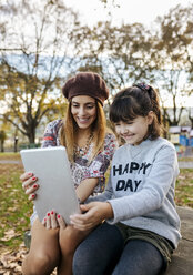 Mother and little daughter taking selfie with tablet in autumnal park - MGOF03187