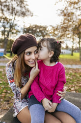 Little girl kissing her mother in autumnal park - MGOF03189