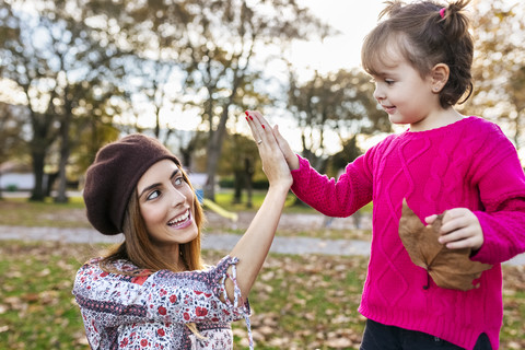 Mutter und Töchterchen geben sich im herbstlichen Park die Klinke in die Hand, lizenzfreies Stockfoto