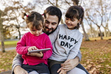 Vater mit seinen kleinen Töchtern beim Betrachten der Tafel im herbstlichen Park - MGOF03195