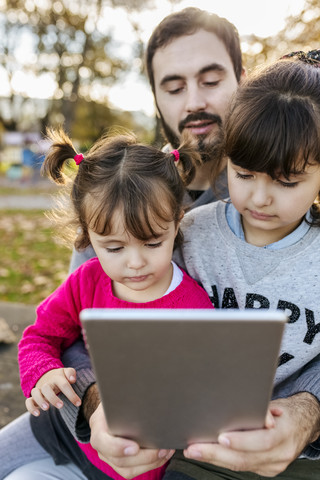 Father with his little daughters looking at tablet stock photo