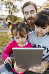 Father with his little daughters looking at tablet - MGOF03196