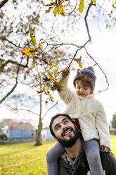 Little girl on shoulders of her father in autumnal park - MGOF03207