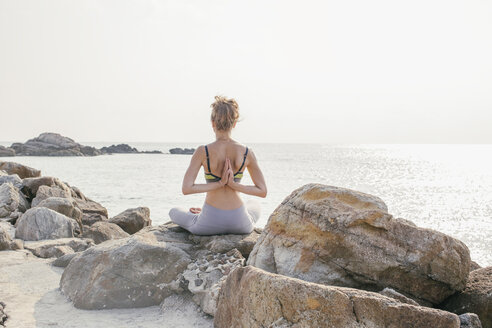Frau sitzt im Lotussitz und meditiert am Strand - MOMF00057