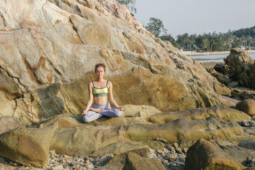 Woman sitting in lotus seat, meditating on the beach - MOMF00061