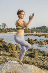 Frau übt Yoga am Strand - MOMF00063