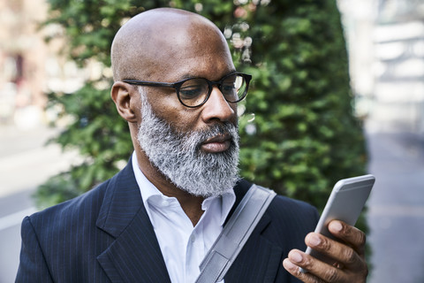 Mature businessman reading smartphone messages stock photo