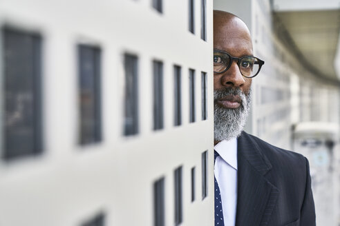 Mature businessman standing by wall, looking worried - FMKF03841