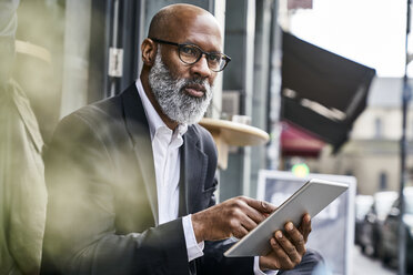 Mature businessman sitting in cafe using digital tablet - FMKF03852