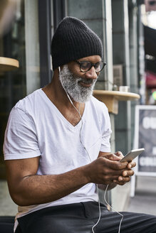 Älterer Mann benutzt Smartphone in einem Café - FMKF03856
