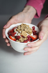 Frau hält Schüssel mit Müsli, Joghurt und Erdbeeren - CHPF00384