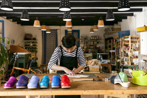 Holzschuhmacherin bei der Arbeit in ihrer Werkstatt, lizenzfreies Stockfoto