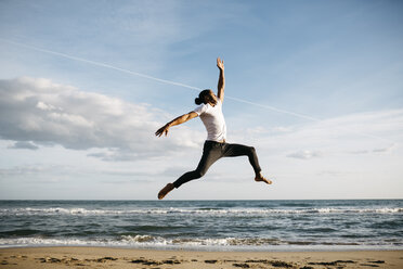 Junger Mann springt am Strand in die Luft - JRFF01301