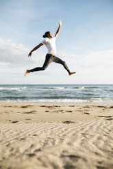 Junger Mann springt am Strand in die Luft - JRFF01302