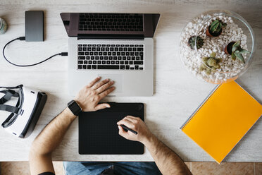 Man working with graphics tablet and laptop at home office, top view - JRFF01304