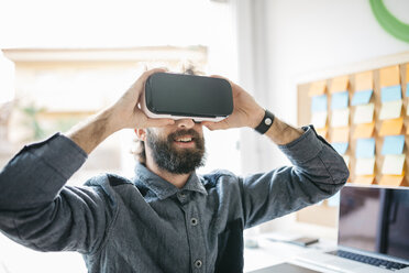 Mann mit Virtual-Reality-Brille arbeitet in seinem Büro an einem neuen Projekt - JRFF01310