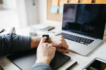 Man using smartwatch at desk - JRFF01316