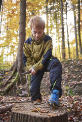 Redheaded boy treating branch with bow in autumnal forest - JEDF00287
