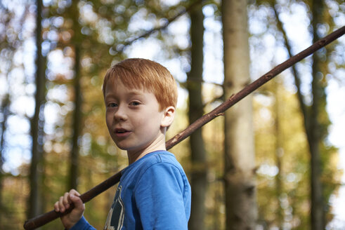 Portrait of redheaded boy with wood stick in the forest - JEDF00290