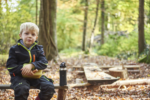 Porträt eines blonden kleinen Jungen beim Mittagessen im Wald, lizenzfreies Stockfoto