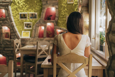 Rückenansicht einer jungen Frau, die an einem Tisch in einem Restaurant sitzt - MOMF00089