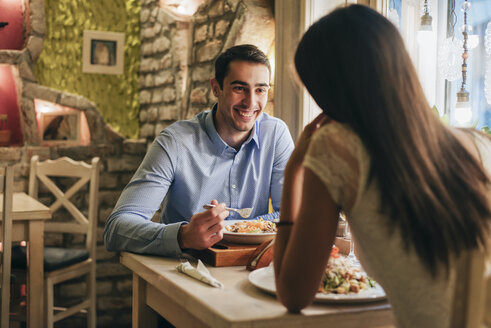 Porträt eines glücklichen jungen Mannes beim Abendessen mit seiner Freundin in einem Restaurant - MOMF00106