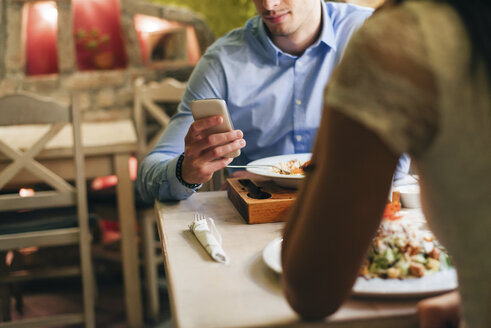 Man checking messages while having dinner in a restaurant - MOMF00107