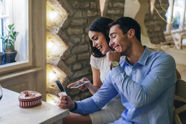 Young couple watching instant photos having fun - MOMF00114