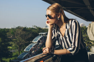 Stylish young woman enjoying sunlight on terrace - MOMF00120