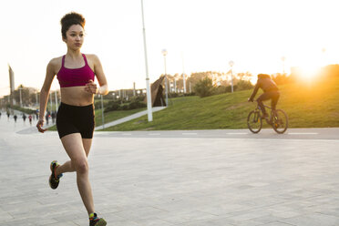 Young woman jogging at evening twilight - KKAF00713