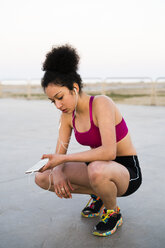 Young jogger with earphoes and cell phone - KKAF00716