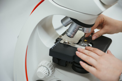 Nahaufnahme eines Laboranten bei der Verwendung eines Mikroskops im Labor, lizenzfreies Stockfoto
