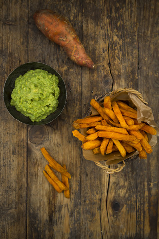 Süßkartoffelpommes und Avocado-Dip auf Holz, lizenzfreies Stockfoto