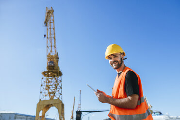 Portrait of smiling port worker using a tablet at work - KIJF01376