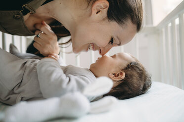 Mutter lächelt ihr Baby in der Krippe an - GEMF01582