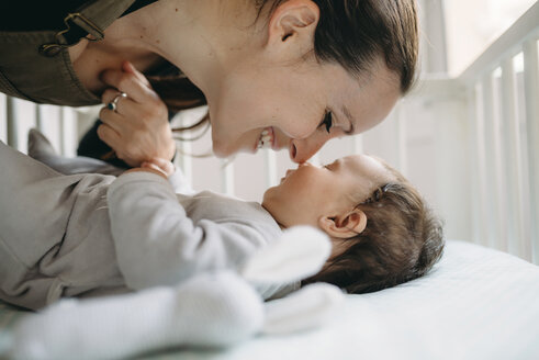 Mother smiling at her baby in the crib - GEMF01582