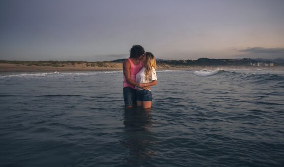 Junges Paar küsst sich im Meer in der Abenddämmerung - DAPF00684