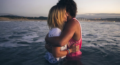 Young couple hugging in the sea at dusk - DAPF00685