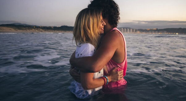 Junges Paar umarmt im Meer in der Abenddämmerung - DAPF00685