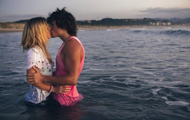 Young couple kissing in the sea at dusk - DAPF00686