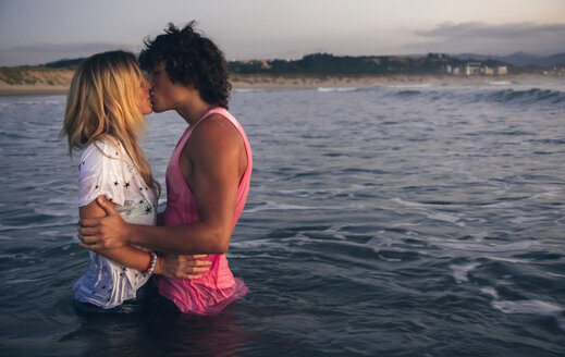 Junges Paar küsst sich im Meer in der Abenddämmerung - DAPF00686