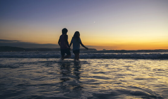 Junges Paar beim Spaziergang im Meer in der Abenddämmerung - DAPF00687