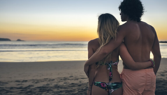 Junges Paar beobachtet den Sonnenuntergang am Strand - DAPF00688